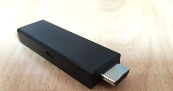 Clé Amazon Fire TV Stick avec son connecteur HDMI posée sur une table en bois