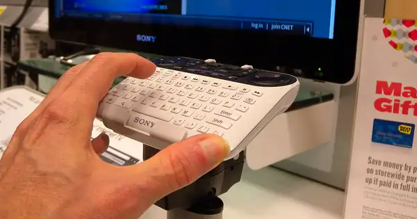 Main utilisant une télécommande clavier devant un téléviseur connecté Sony