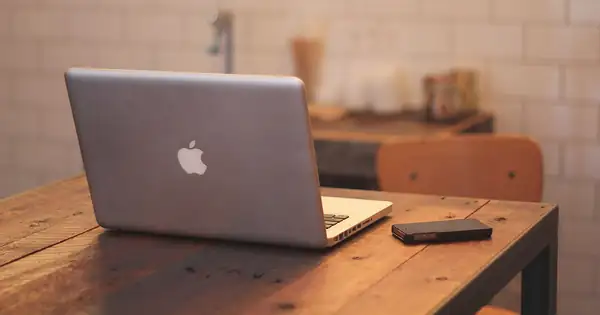 Ordinateur portable MacBook ouvert sur un bureau en bois à côté d’un iPhone